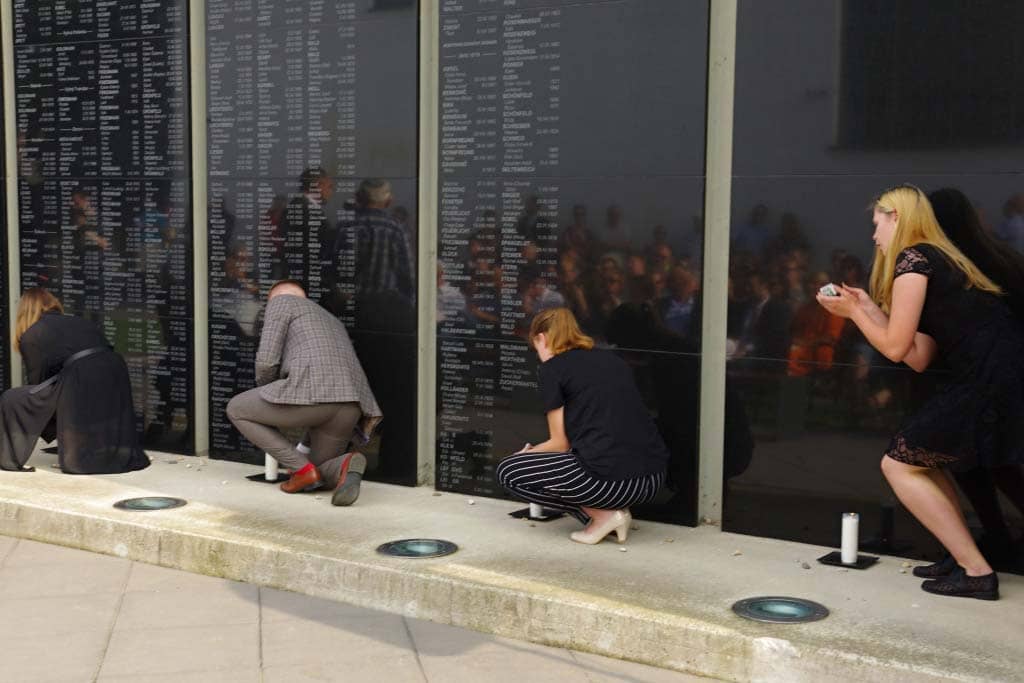 Local students from Leonard Stockel High School light memorial candles in front of the name tablets