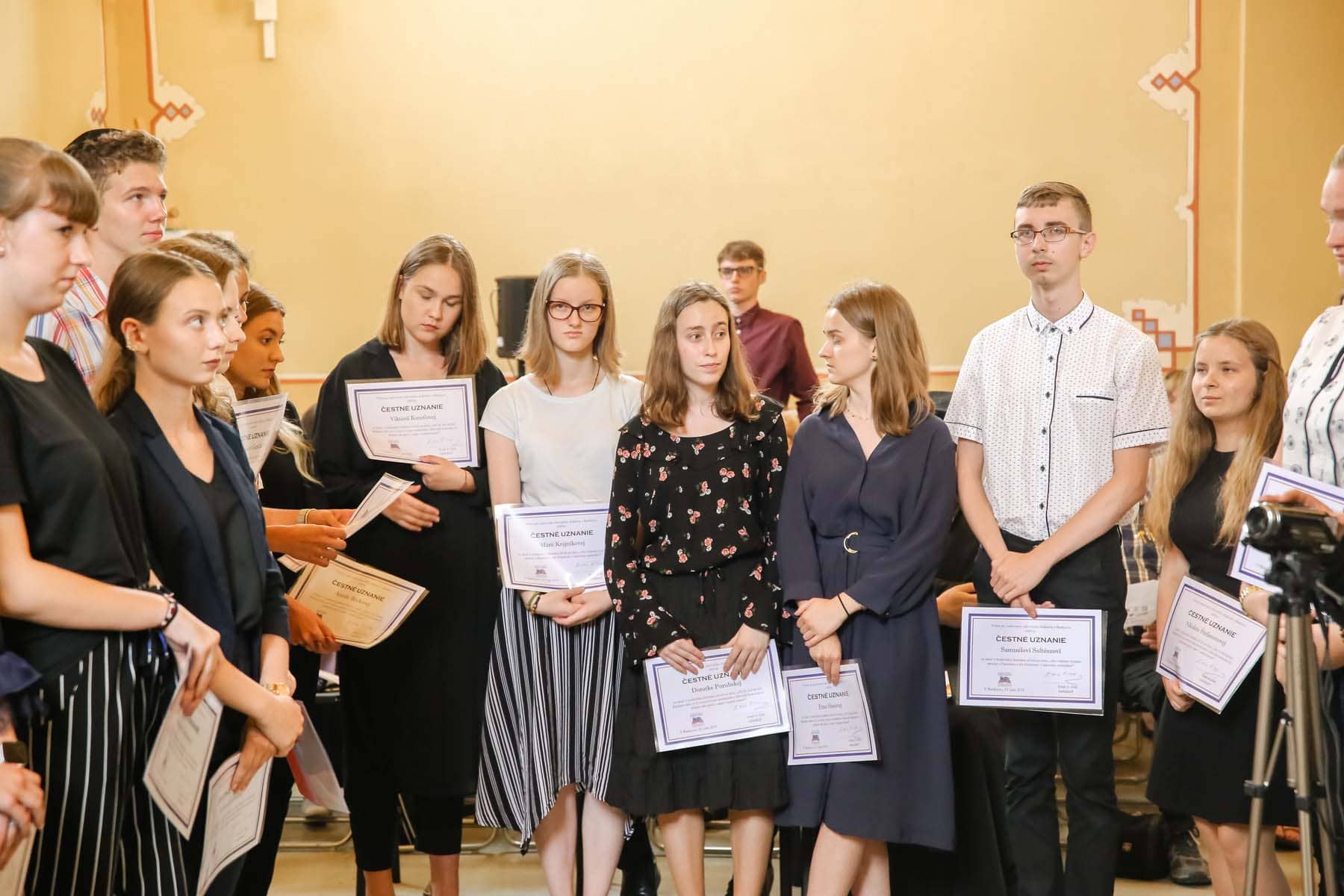 Participants of the Essay Contest stand on stage with their certificates